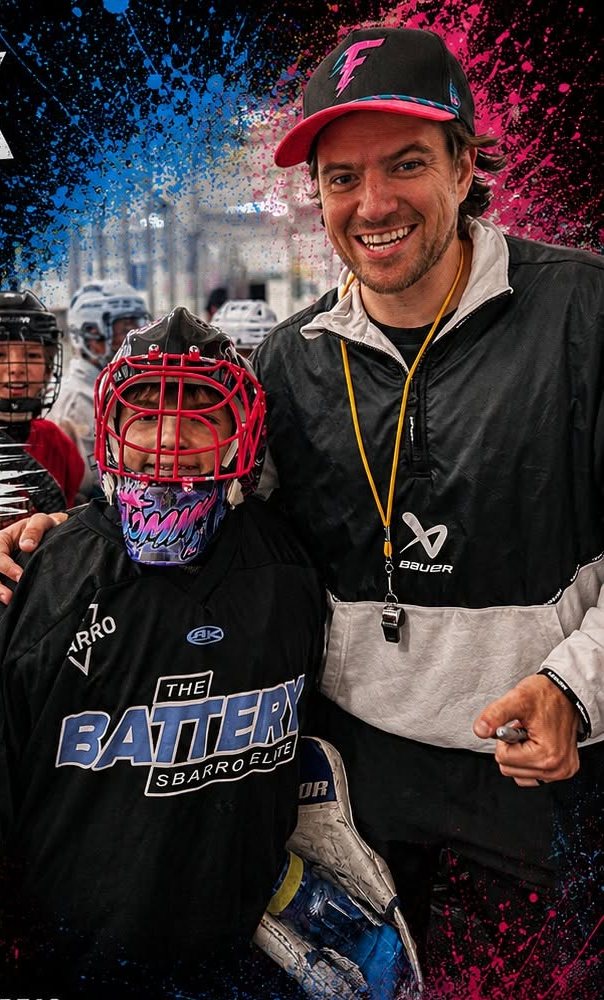 A young goalie in a custom mask with a coach at the rink
